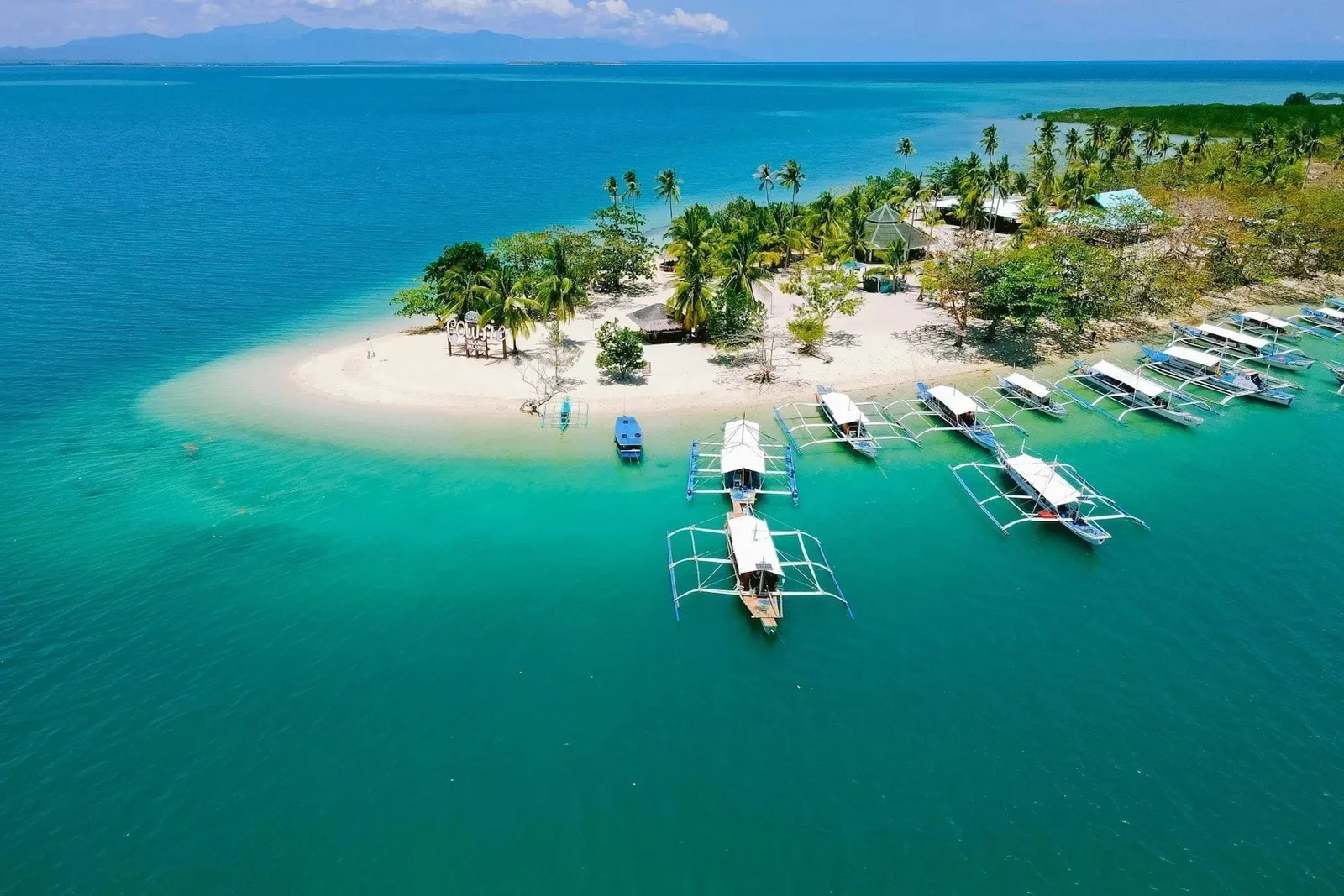 Aerial view of Cowrie Island in Honda Bay, with its white beach, palm trees and island-hopping boats